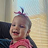 baby, child, toddler, smiling, portrait, indoor, pink_bow, hair_bow, pink_clothing, heart_pattern, face, teeth, sitting, chair, window, blinds, sunlight, close_up, happy, photography