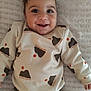 baby, child, smiling, face, sweater, clothing, lying_down, blanket, happy, indoor, portrait, infant, cute, person, toddler, long_sleeve, pattern, brown_pants, texture, cozy