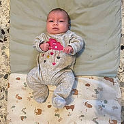 Ambre a rejoint le concours — aidez-le/la à gagner de superbes lots ! baby, infant, onesie, clothing, blanket, cushion, floor, pattern, animal_print, face, person, lying_down, cute, indoor, newborn, baby_garment, expression, comfort, soft_texture, small_hands