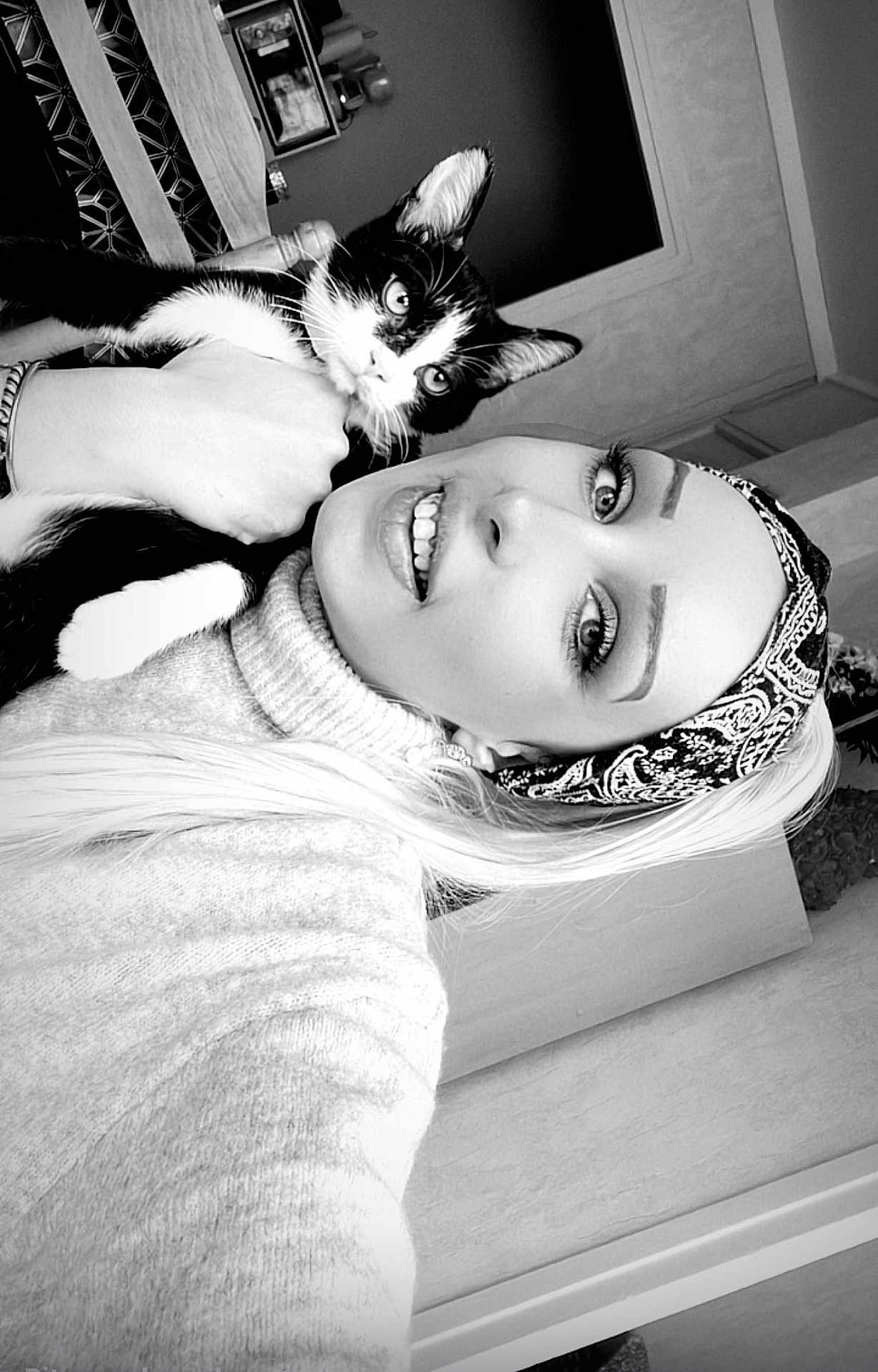 Simba participe au concours pour gagner de l'argent avec cette photo : woman, cat, black_and_white, headband, sweater, indoor, portrait, smile, pet, holding, face, closeup, furniture, curious, happy, eyelashes, cozy, hair, eyes, person