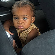 Jayceveon is registered to the contest to win money with this photo: child, toddler, car, car_seat, bottle, braided_hair, earring, curious, brown_skin, clothing, seatbelt, interior, vehicle, person, portrait, looking, sitting, young_child, indoors, expression