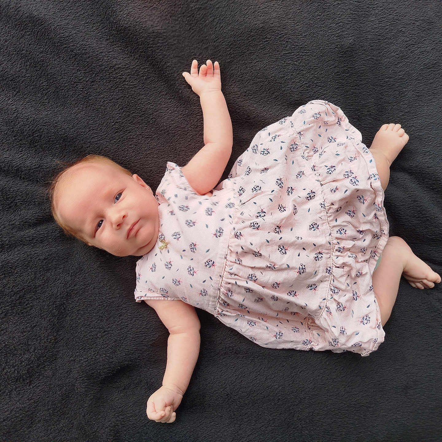 Emma participe au concours pour gagner de l'argent avec cette photo : baby, blanket, blue_eyes, casual, child, cute, dress, expression, face, floral_pattern, foot, hand, infant, lying_down, newborn, person, pink, portrait, skin, soft_texture