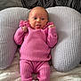 Maisie joined the competition — help win amazing prizes! baby, infant, pink_clothing, socks, tongue_out, cushion, blanket, pillow, soft_texture, indoor, cute, playful, child, person, portrait, resting, comfortable, smiling, cozy, small