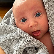 Maisie joined the competition — help win amazing prizes! baby, blanket, blue_eyes, closeup, curious, face, fluffy, gray, hand, indoor, infant, mouth_open, person, portrait, skin, soft, towel, wide_eyes, wrapped, young_child