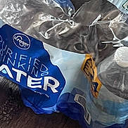 Ketchup is registered to the contest to win money with this photo: barcode, blue, cat, closeup, container, curious, eye, floor, foil, indoor, object, packaging, pet, plastic, reflection, texture, transparent, water_bottle, white, yellow