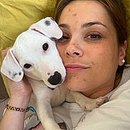 Floki a rejoint le concours — aidez-le/la à gagner de superbes lots ! woman, puppy, dog, pet, cuddling, face, earrings, bracelet, bed, pillow, casual, portrait, indoor, closeup, white_dog, spots, happy, relaxed, friendship, skin