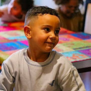 Amir participe au concours pour gagner de l'argent avec cette photo : child, boy, smiling, indoor, table, colorful, haircut, person, casual_clothing, happy, face, portrait, seated, people, background, home, family, candid, young, expression