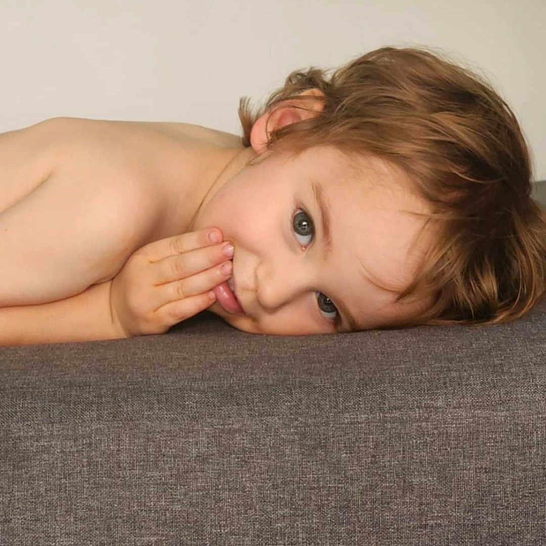 Jules participe au concours pour gagner de l'argent avec cette photo : brown_hair, casual, child, closeup, couch, curious, expression, face, gray, hand, head, indoor, lying_down, person, playful, portrait, resting, skin, smile, young