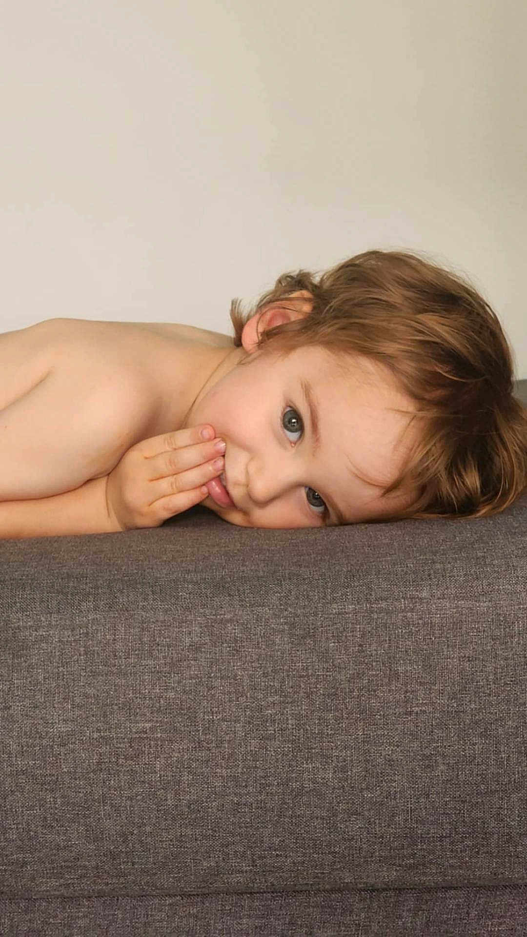 Jules participe au concours pour gagner de l'argent avec cette photo : child, young, face, hand, brown_hair, couch, gray, resting, playful, curious, indoor, portrait, expression, skin, person, smile, casual, head, lying_down, closeup