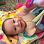 baby, infant, play_mat, toy, soft_toy, colorful, smile, happy, child, carpet, floor, clothing, cute, face, person, indoors, playtime, book, hand, bright