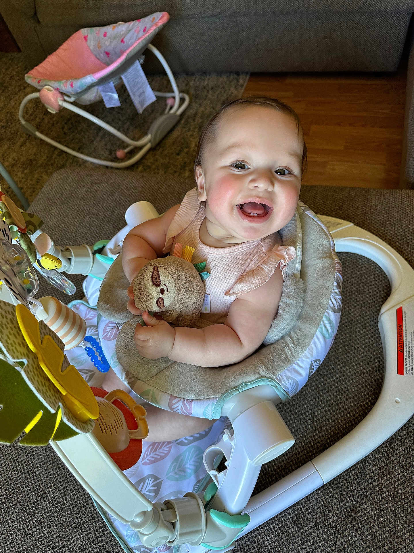 Jazlyn is registered to the contest to win money with this photo: baby, child, smiling, plush_toy, baby_seat, toy, indoor, happy, person, couch, furniture, floor, wood_floor, clothing, infant, cute, playful, seat, home, cheerful