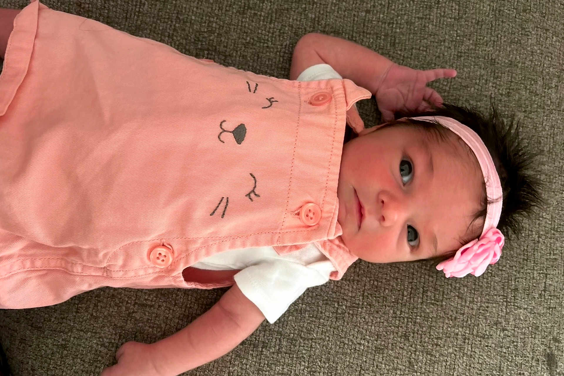 Mia is registered to the contest to win money with this photo: baby, infant, pink_outfit, headband, flower, carpet, cute, portrait, child, clothing, lying_down, small_hands, expression, person, indoor, soft_lighting, face, newborn, adorable, young_child