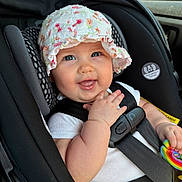 Nova Rae joined the competition — help win amazing prizes! baby, child, car_seat, hat, floral, smile, toy, colorful, seatbelt, safety, infant, cute, happy, indoors, person, clothing, closeup, portrait, headwear, hand