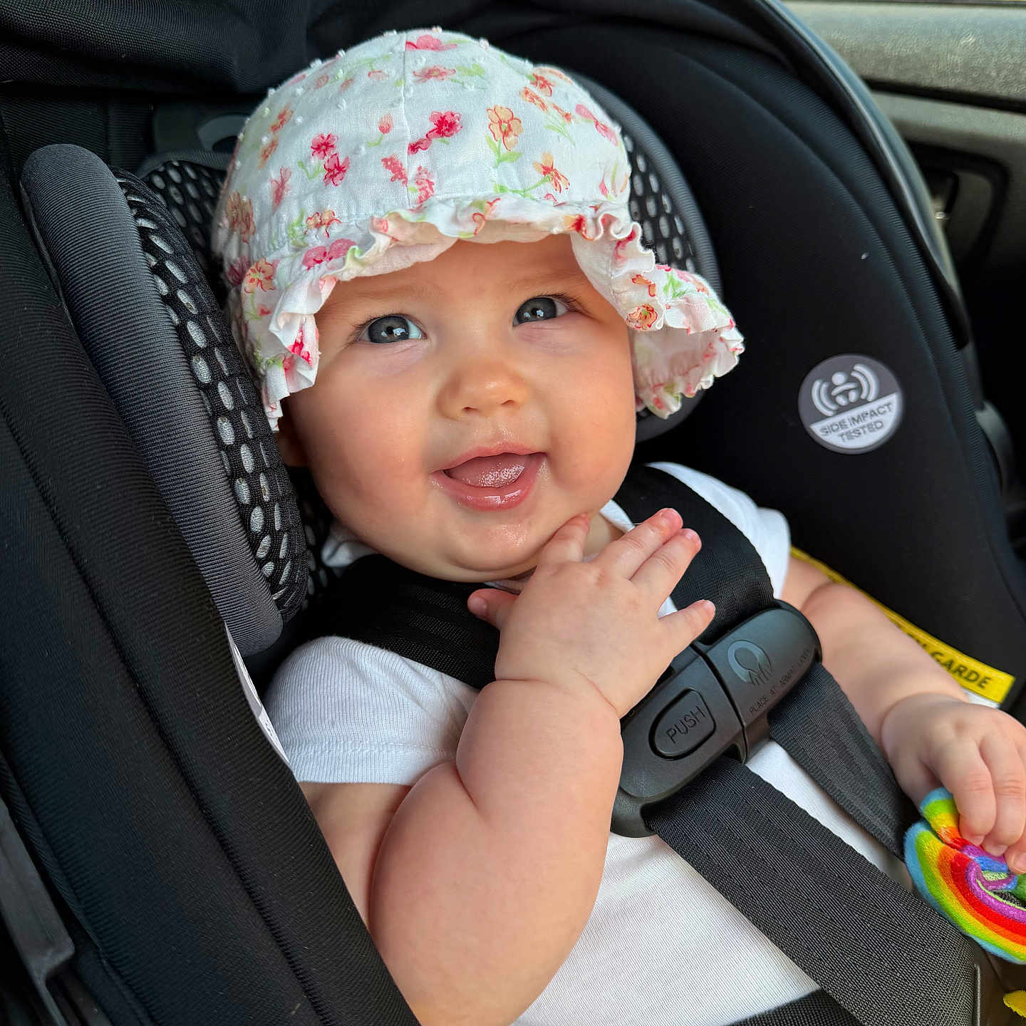 Nova Rae joined the competition — help win amazing prizes! baby, child, car_seat, hat, floral, smile, toy, colorful, seatbelt, safety, infant, cute, happy, indoors, person, clothing, closeup, portrait, headwear, hand