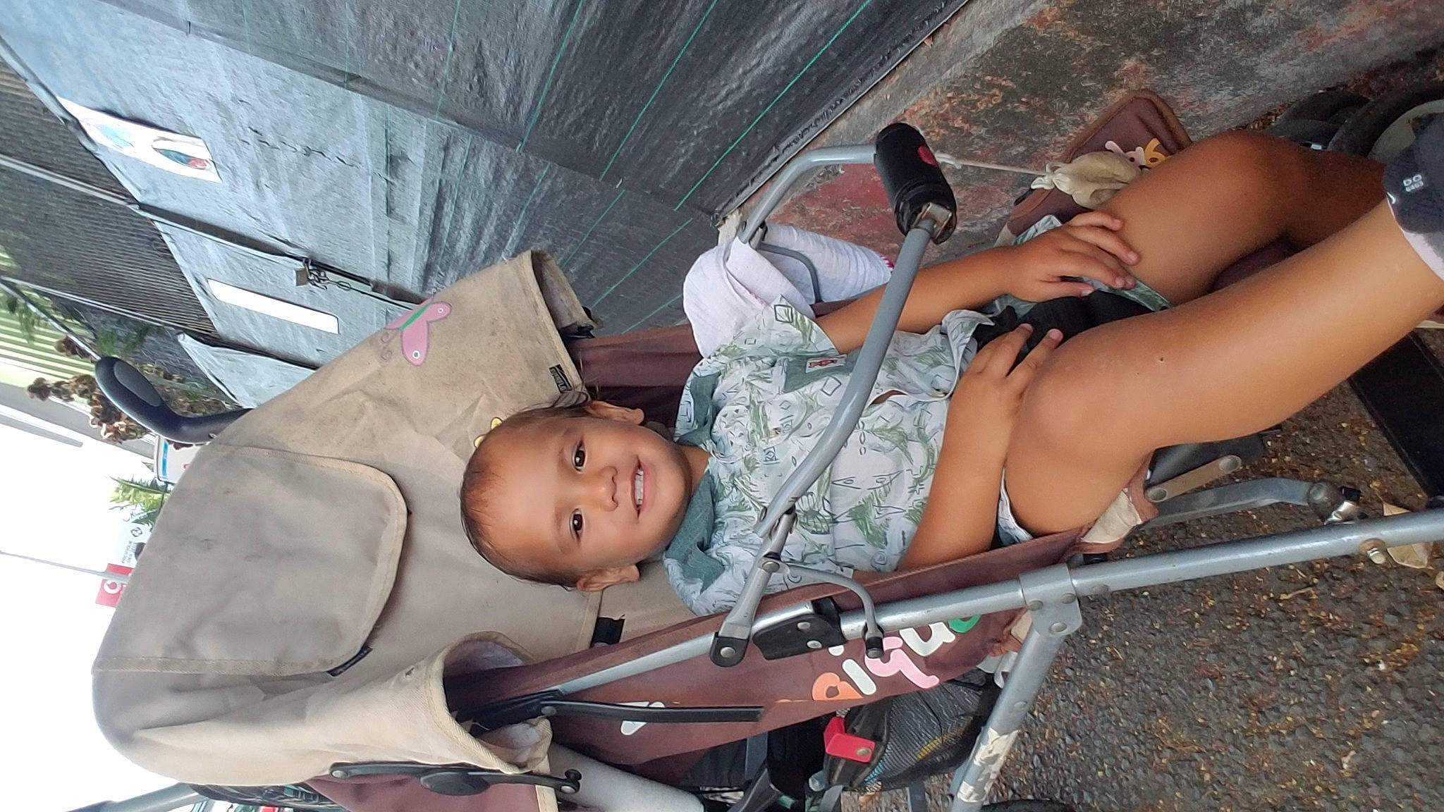 Rahiti Namataoterai Isaac participe au concours pour gagner de l'argent avec cette photo : baby, baby_carriage, child, comfort, eyewear, foot, fun, human_leg, joy, lap, leisure, person, public_space, recreation, sandal, shorts, sitting, skin, sunglasses, thigh