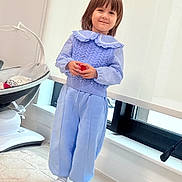 Sabrina joined the competition — help win amazing prizes! child, toddler, smiling, portrait, standing, indoor, blue_outfit, sweater, collar, pants, striped_socks, red_toy, window, curtains, baby_rocker, chair, carpet, home, natural_light, full_body