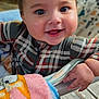 baby, infant, smiling, close_up, plaid, onesie, blanket, hand, big_eyes, chubby_cheeks, mouth_open, play_seat, patterned_fabric, soft_toy, indoor, portrait, cute, happy, sitter, toddler