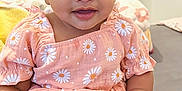 Anette is registered to the contest to win money with this photo: baby, child, infant, dress, headband, flower_pattern, daisy, smile, cute, indoors, sitting, soft_surface, skin, hand, foot, black_hair, large_eyes, pink, comfortable, adorable