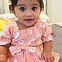 baby, child, infant, dress, headband, flower_pattern, daisy, smile, cute, indoors, sitting, soft_surface, skin, hand, foot, black_hair, large_eyes, pink, comfortable, adorable