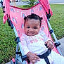 baby, girl, stroller, pink, rainbow, outdoor, grass, sidewalk, smile, pigtails, clothing, onesie, child, happy, seatbelt, metal_frame, daylight, nature, cute, portrait