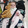 Serena is registered to the contest to win money with this photo: baby, plush_toy, giraffe, stroller, blanket, shopping_aisle, floor, product_shelves, pacifier, clothing, infant, person, baby_bib, safety_strap, store, indoor, retail, shopping_cart, cute, child