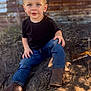 toddler, child, boy, blue_eyes, black_tshirt, jeans, boots, sitting, outdoor, dirt, top_knot, curious, portrait, daylight, rustic, wooden_wall, casual_clothing, young, cute, nature