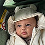 baby, child, hoodie, coat, car_seat, face, eyes, skin, infant, cute, warm_clothing, zipper, ears, soft_texture, portrait, indoor, seatbelt, car_interior, warning_label, closeup