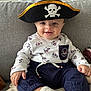 Léon a rejoint le concours — aidez-le/la à gagner de superbes lots ! baby, child, pirate_hat, smiling, sitting, couch, indoor, cute, clothing, long_sleeve, pants, white_socks, face, headwear, infant, portrait, happy, playful, home, costume