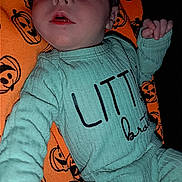 Braxton is registered to the contest to win money with this photo: baby, infant, child, clothing, green_outfit, blanket, orange_blanket, jack_o_lantern, pumpkin_pattern, face, hand, lying_down, cute, expression, indoors, portrait, young_child, sleepwear, fabric, person