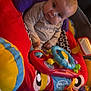 Axel is registered to the contest to win money with this photo: baby, balls, child, colorful, curious, cute, developmental_toys, early_childhood, face, indoor, infant, person, play_area, playmat, plush, seated, soft_toys, steering_wheel_toy, striped_shirt, toy