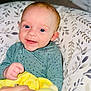 Kit is registered to the contest to win money with this photo: baby, blanket, blue_eyes, child, clothing, comfort, cozy, cushion, cute, face, green_outfit, hand, happy, indoor, infant, pattern, person, portrait, smiling, soft_toys