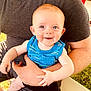 Kit is registered to the contest to win money with this photo: adult, arm, baby, beard, blue_tank_top, casual_clothing, child, face, grass, happy, holding, nature, outdoor, person, red_cup, shorts, sitting, smiling, sunlight, table