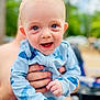 baby, child, blue_outfit, shark_print, smiling, happy, face, hands, person, closeup, portrait, outdoor, blurred_background, skin, infant, cute, joyful, bright_eyes, holding, human
