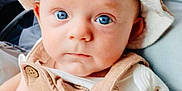 Kit is registered to the contest to win money with this photo: baby, background_people, blue_eyes, child, closeup, clothing, cute, expression, face, hands, hat, holding_hands, indoor, infant, parent, person, seated, skin, soft_light, window