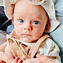 baby, background_people, blue_eyes, child, closeup, clothing, cute, expression, face, hands, hat, holding_hands, indoor, infant, parent, person, seated, skin, soft_light, window