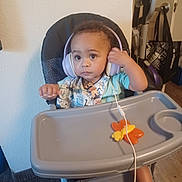 Azrael joined the competition — help win amazing prizes! toddler, child, headphones, high_chair, toy, butterfly, indoor, carpet, vacuum_cleaner, door, bag, floor, wall, clothing, person, baby, expression, seat, tray, curious