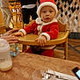 adult, baby, child, cutlery, dining, festive, glass, hand, highchair, interior, lamp, milk_bottle, portrait, restaurant, santa_hat, santa_suit, seat, table, tiled_wall, wood_floor