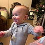 Seth joined the competition — help win amazing prizes! baby, toddler, child, smiling, standing, onesie, living_room, couch, christmas_tree, television, carpet, furniture, happy, portrait, candid, closeup, hands, cheeks, holiday, stain_on_clothing