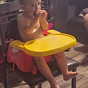 Zander joined the competition — help win amazing prizes! toddler, child, booster_seat, high_chair, eating, snack, indoor, chair, wooden_floor, yellow_tray, furniture, barefoot, curly_hair, young_child, home, casual, person, table, seat, light
