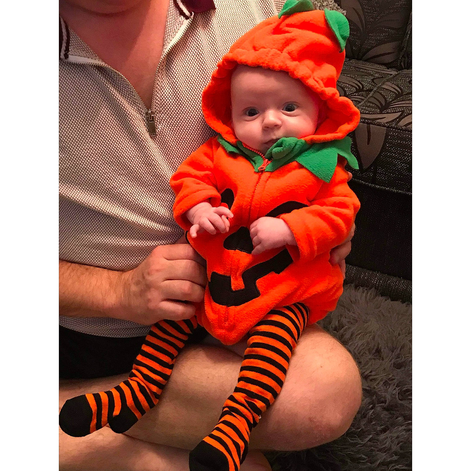 Toby is registered to the contest to win money with this photo: baby, baby_products, baby_toddler_clothing, cap, child, comfort, costume_hat, happy, hat, headwear, human_body, human_leg, lap, leg, orange, outerwear, person, plant, sleeve, thigh