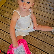 Yzïa participe au concours pour gagner de l'argent avec cette photo : toddler, child, girl, pigtails, white_dress, blue_eyes, magnetic_drawing_board, pink_toy, wooden_deck, outdoor, sitting, playing, drawing, innocence, curious, toy, floor, casual, summer, barefoot