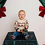 Jules a rejoint le concours — aidez-le/la à gagner de superbes lots ! child, toddler, smiling, sweater, reindeer_sweater, jeans, shoes, ornament, jingle_bell, holiday, christmas, festive, portrait, studio, curtain, green_curtain, red_bow, table, decoration, indoor