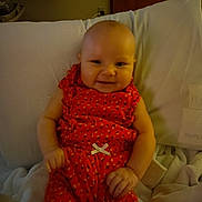 Kierralynn is registered to the contest to win money with this photo: baby, infant, smile, orange_outfit, pillow, blanket, indoor, child, cute, happy, person, clothing, seated, hands, face, head, young_child, cozy, fabric, rest