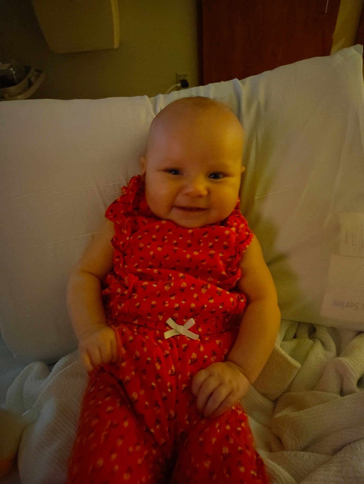 Kierralynn is registered to the contest to win money with this photo: baby, infant, smile, orange_outfit, pillow, blanket, indoor, child, cute, happy, person, clothing, seated, hands, face, head, young_child, cozy, fabric, rest