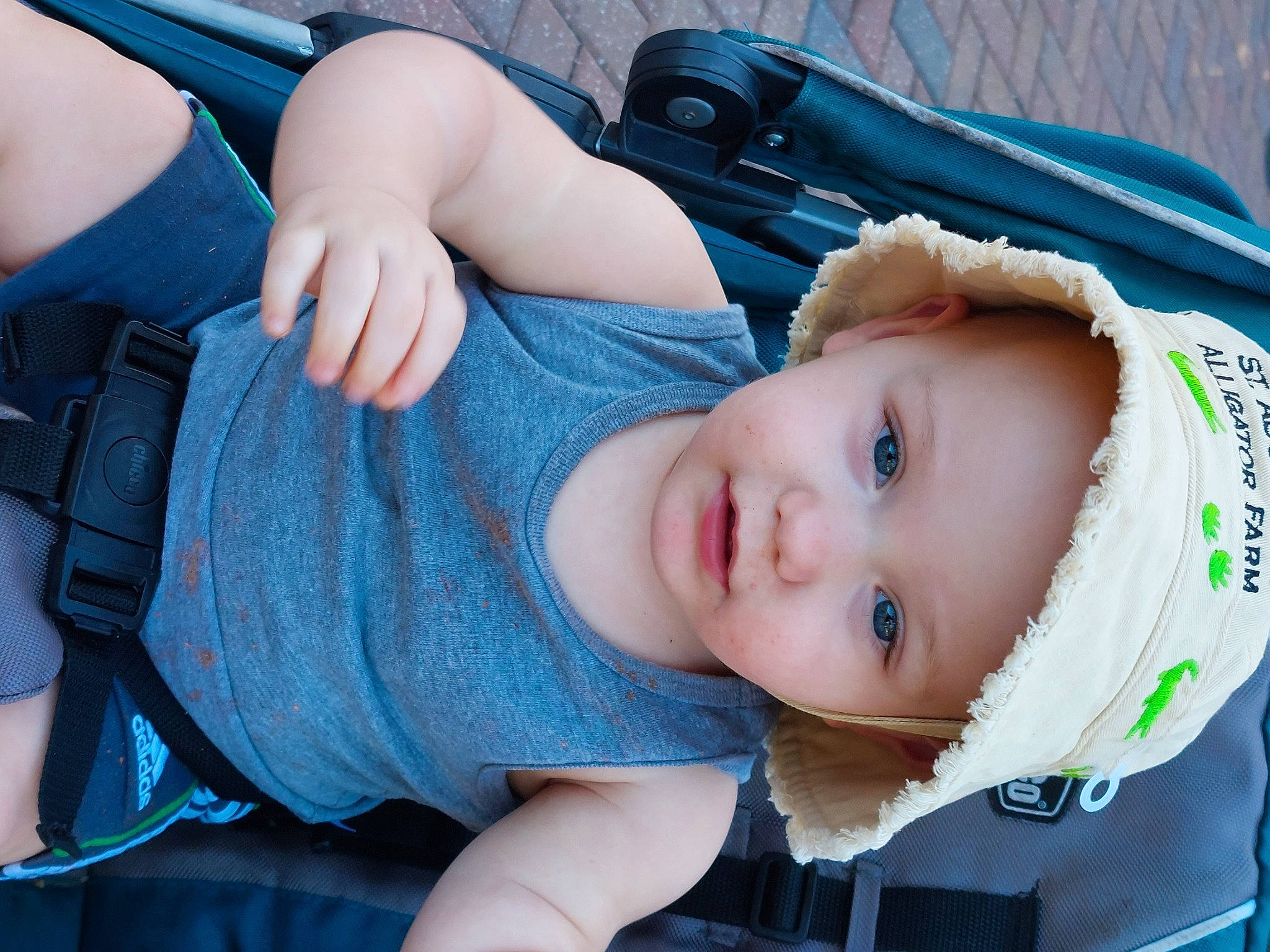 Sheldon is registered to the contest to win money with this photo: baby, baby_products, baby_toddler_clothing, blue, cheek, child, comfort, electric_blue, fashion_accessory, gesture, grass, hand, hat, headwear, mouth, pattern, person, product, sitting, skin