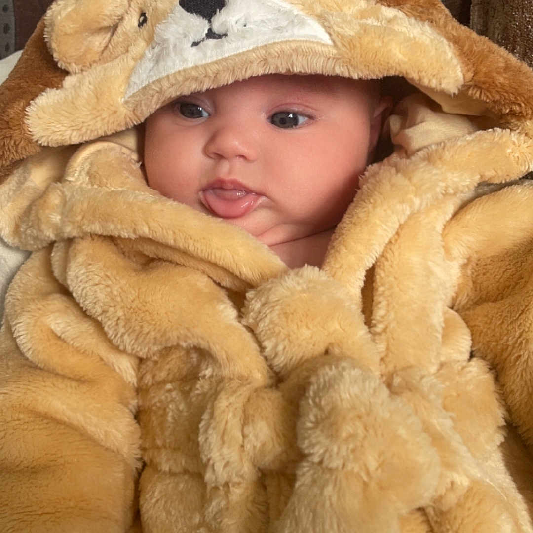Willow is registered to the contest to win money with this photo: baby, blanket, bonnet, cap, clothing, coat, face, fur, hat, head, hood, hoodie, knitwear, newborn, person, photography, portrait, sweater, sweatshirt, towel