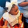 Sayuri is registered to the contest to win money with this photo: baby, child, headband, bow, bib, high_chair, wooden_furniture, polka_dot, bracelet, earrings, curly_hair, person, socks, indoor, carpet, casual_clothing, seated, cute, infant, holding