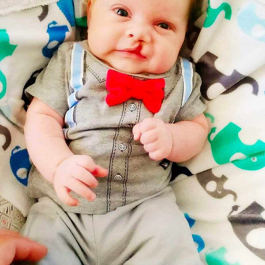 Logan is registered to the contest to win money with this photo: accessories, baby, bowtie, clothing, cushion, face, formalwear, furniture, happy, head, homedecor, jeans, newborn, pants, person, photography, portrait, shorts, smile, tie