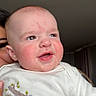 Hudson is registered to the contest to win money with this photo: baby, child, infant, onesie, sloth, drool, face, smile, happy, cute, cheeks, person, indoor, curtains, adult, holding, closeup, portrait, head, toddler