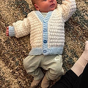 Hudson is registered to the contest to win money with this photo: baby, blue, cardigan, carpet, child, cozy, cute, floor, indoors, infant, knitwear, lying_down, nike_logo, pants, person, resting, socks, soft_lighting, texture, white